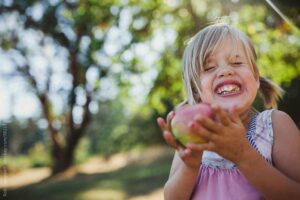 Fröhliches Kind isst einen Apfel Zahnärzte Teltow